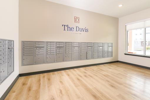 A room with a wall of mailboxes and a sign that says The Davis.