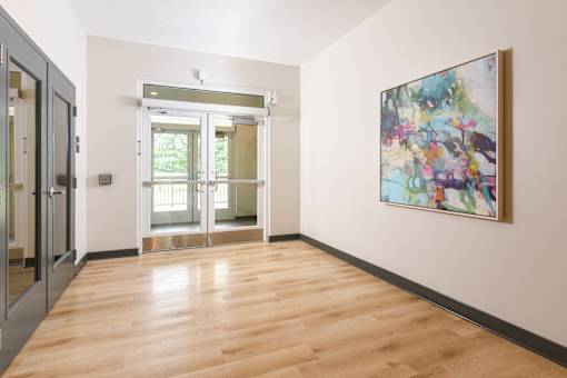 A hallway with a wooden floor and a painting on the wall.
