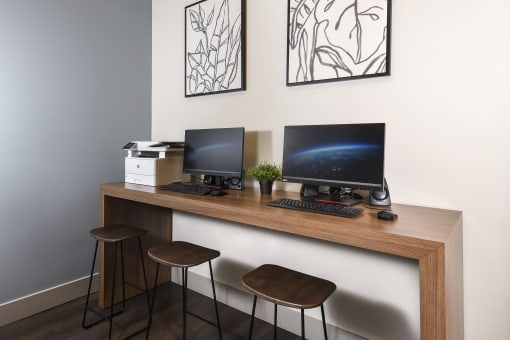 a desk with two computer monitors and two stools