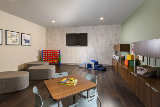 a room with a table and chairs and a television on the wall