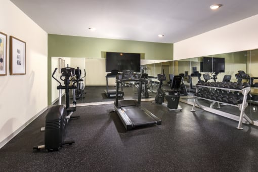a large fitness room with cardio equipment and a flat screen tv