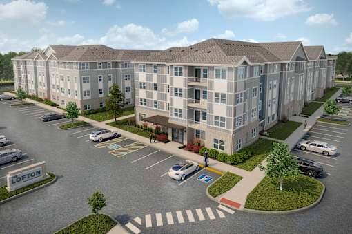 A large apartment complex with a parking lot in front.