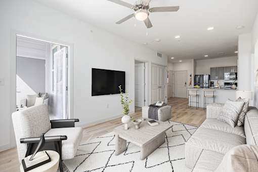 A modern living room with a white sofa, a black and white rug, and a flat-screen TV mounted on the wall.