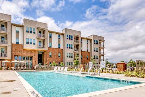 A large swimming pool is in front of apartment buildings.
