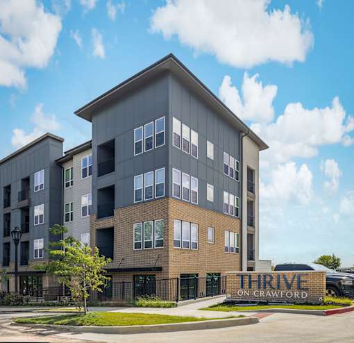 A modern multi-story building with the sign "THRIVE ON CRAWFORD" in front.