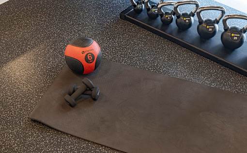 A set of kettlebells is on a mat with a dumbbell on top of it.