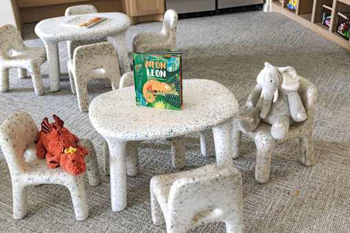 A book titled Neon Leon sits on a white table surrounded by white chairs.