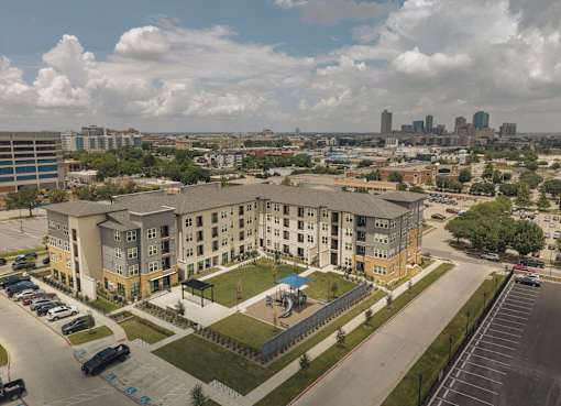 A large apartment complex with a parking lot in front.
