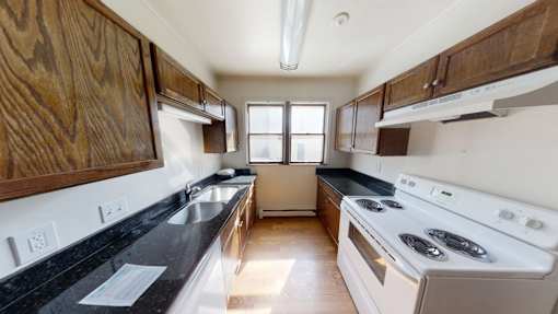 A kitchen with a stove, sink, and cabinets.