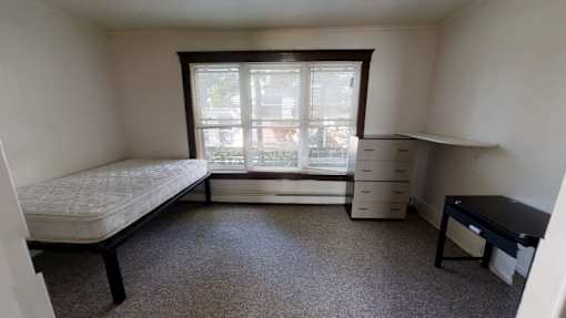 A bedroom with a bed, dresser, and desk.
