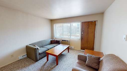 A living room with a brown couch, a grey couch, and a wooden coffee table.