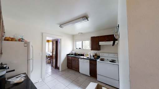 A kitchen with white appliances and a black counter.