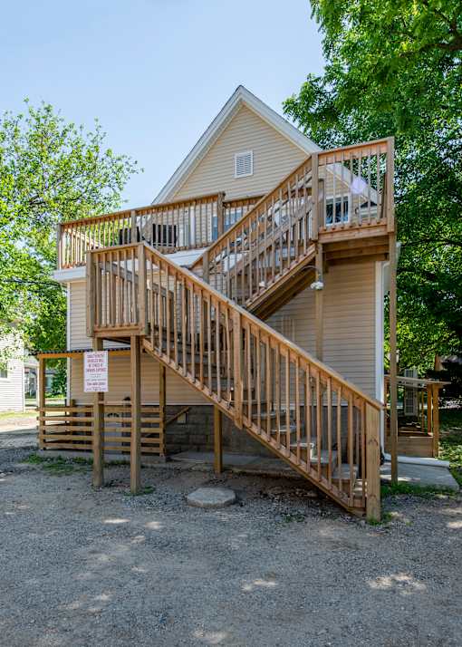 A house with a wooden deck and stairs leading to the second floor.