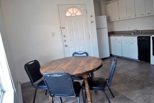 A kitchen with a table and chairs in the foreground.