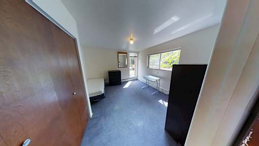 A room with a brown door, a black chair, and a white sofa.