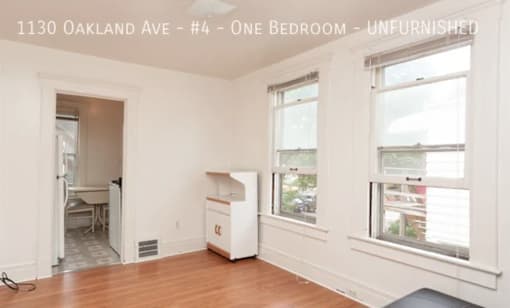 A room with a white fridge and a window.