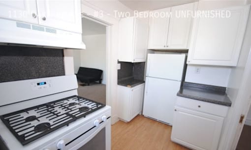 A white kitchen with a stove top oven and a refrigerator.
