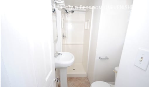 A white bathroom with a toilet, sink, and shower.