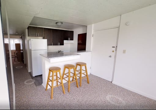 A kitchen with a white fridge and wooden stools.
