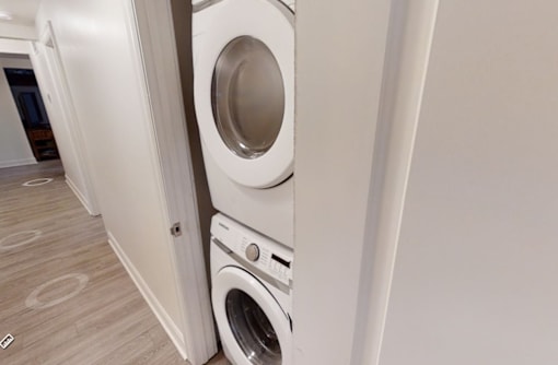 A white washing machine is stacked on top of another in a laundry room.