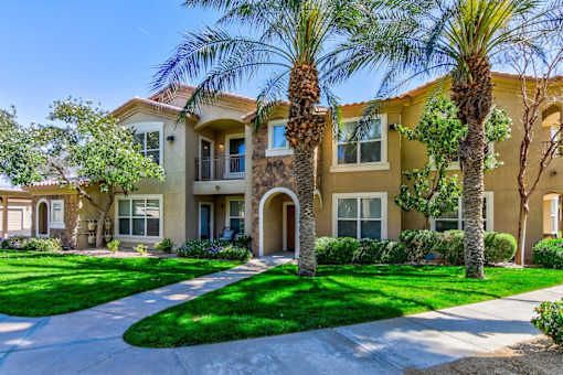 A row of houses with palm trees in front.