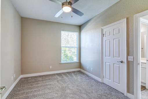 A room with a ceiling fan and a door.