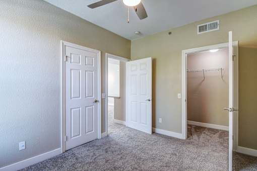 A room with a carpeted floor and three doors.