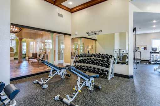 A gym with a row of dumbbells and a sign that says "Results = Excuses".