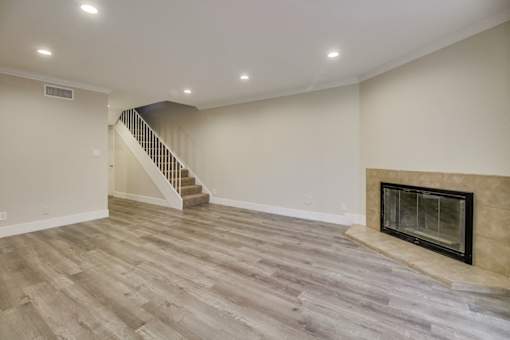 A living room with a fireplace and a staircase.