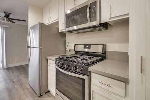 A modern kitchen with a stainless steel refrigerator, microwave, and stove.