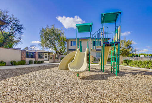 A playground with a slide and a green structure.