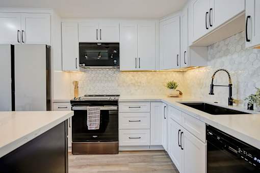 A kitchen with white cabinets and a black oven.
