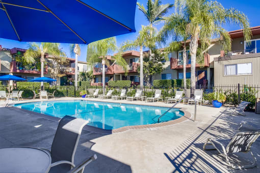 a resort style swimming pool with chaise lounge chairs and umbrellas
