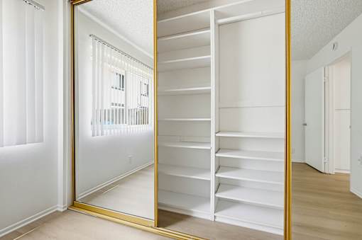 A white closet with a mirror and shelves.