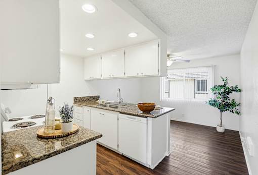 A kitchen with white cabinets and a granite countertop.
