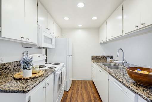 A kitchen with granite countertops and white cabinets.