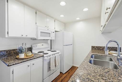 A kitchen with white cabinets and a granite countertop.