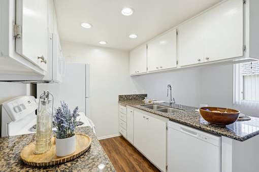 A kitchen with white cabinets and a granite countertop.