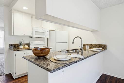 A kitchen with a granite countertop and white cabinets.