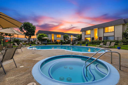 A hot tub sits in the middle of a patio with chairs around it.