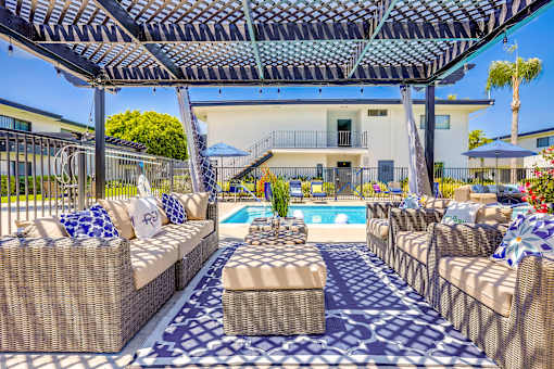 A patio with a pool and a wicker sofa.