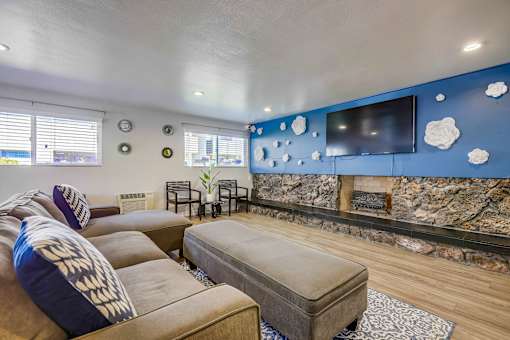 A living room with a stone fireplace and a flat screen TV.