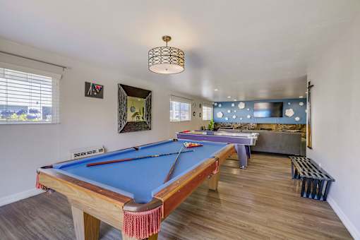 A pool table with red cloth and white balls is in the center of the room.