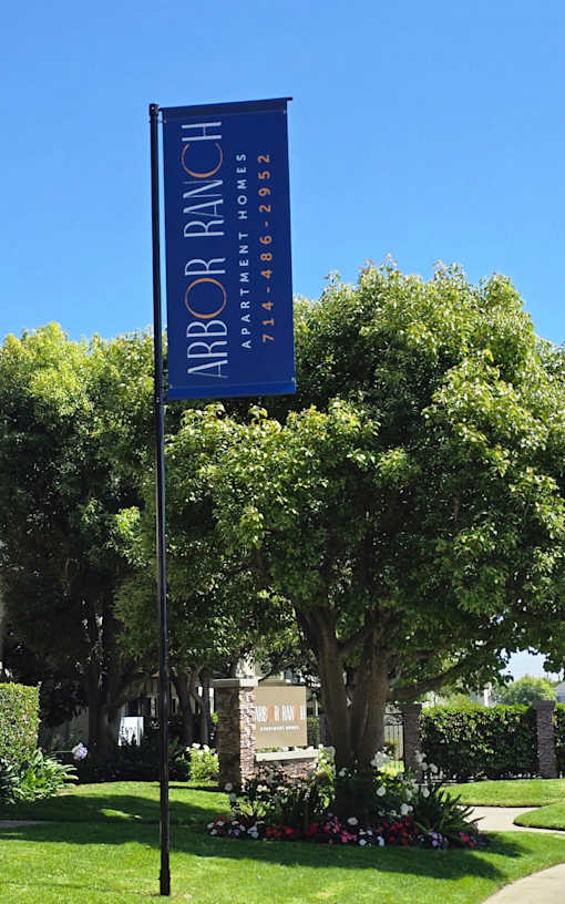 Lush garden landscaping with mature trees and community signage.