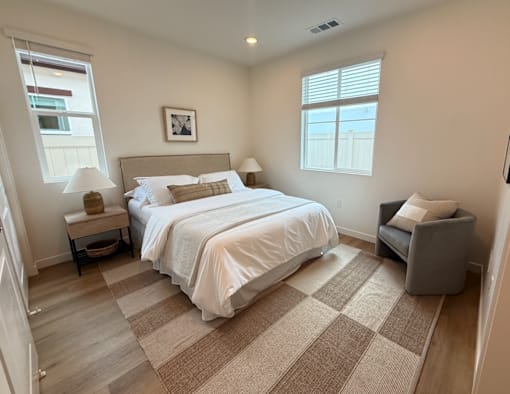 A bedroom with a large bed and a chair.