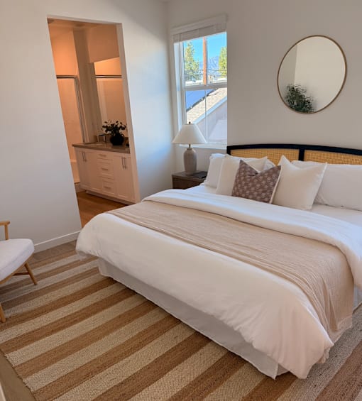 A bedroom with a large bed and a striped rug.