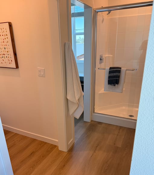 A bathroom with a glass shower door and a towel hanging on the door.