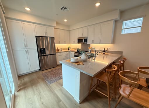A kitchen with a white counter and wooden chairs.
