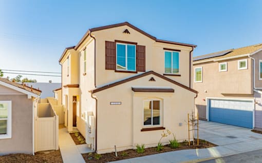 A beige house with a brown roof and a blue garage door.