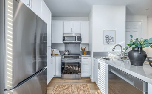 A modern kitchen with a stainless steel refrigerator and white cabinets.